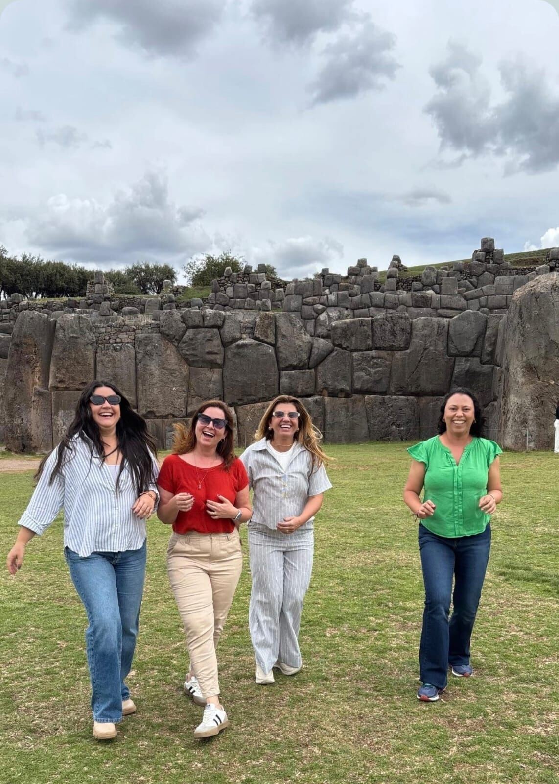 Quatro mulheres caminhando sorrindo diante das muralhas incas em Cusco