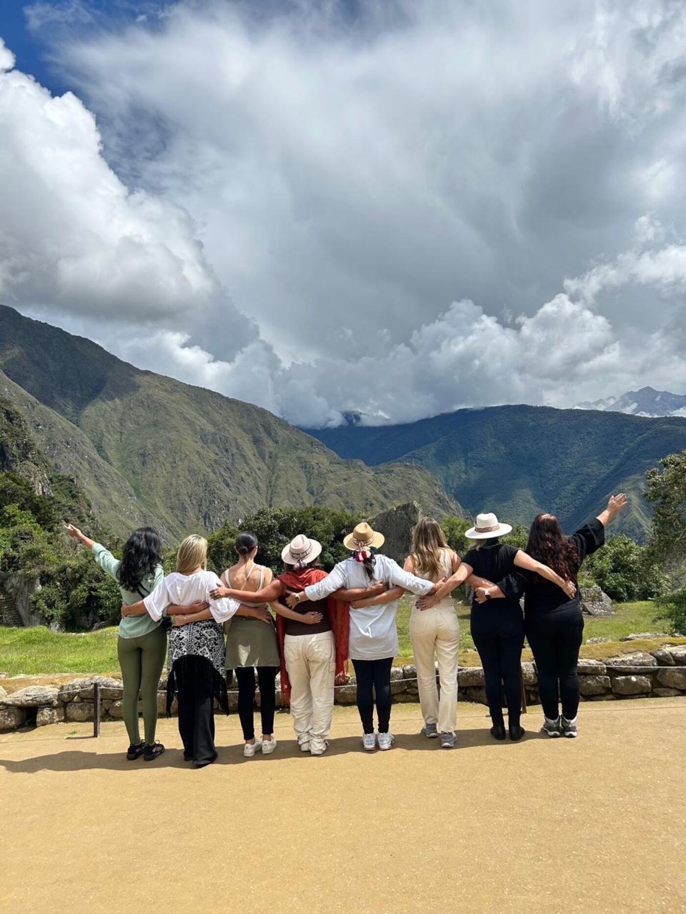 Grupo de mulheres abraçadas contemplando as montanhas em Machu Picchu