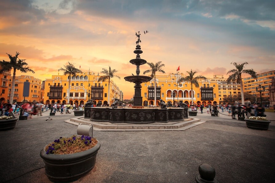 Plaza de Armas de Lima ao entardecer, com a fonte e os casarios coloniais amarelos